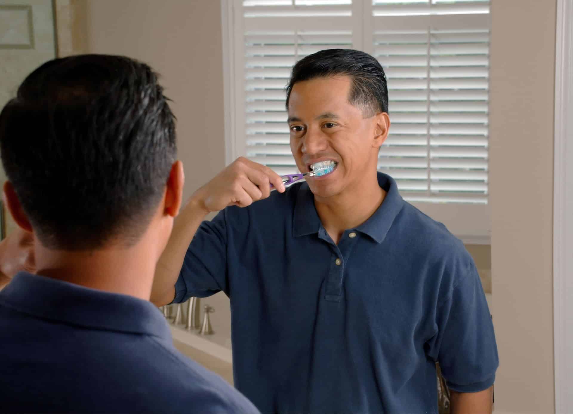 man brushing teeth in the mirror