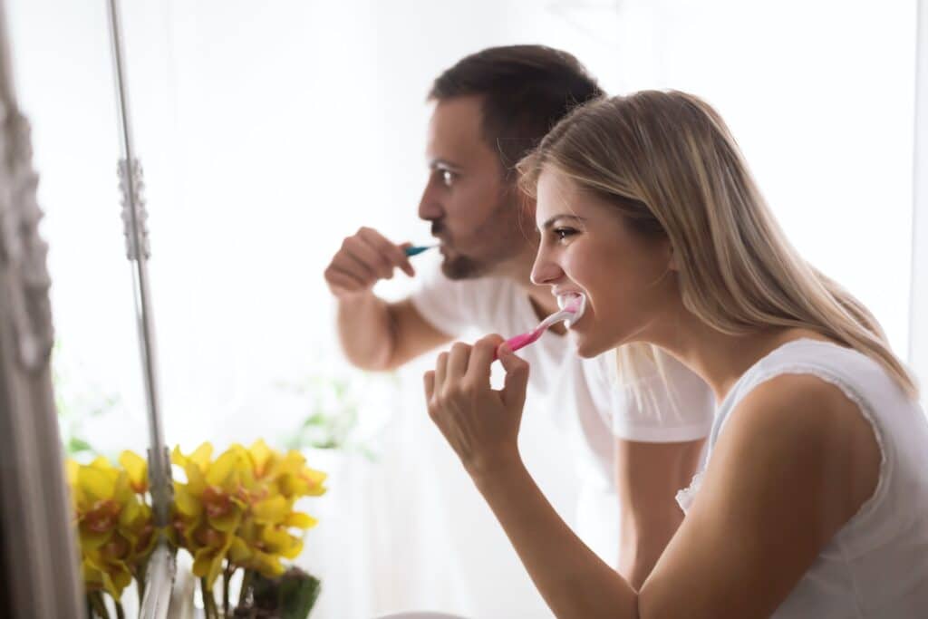 man and woman brushing teeth