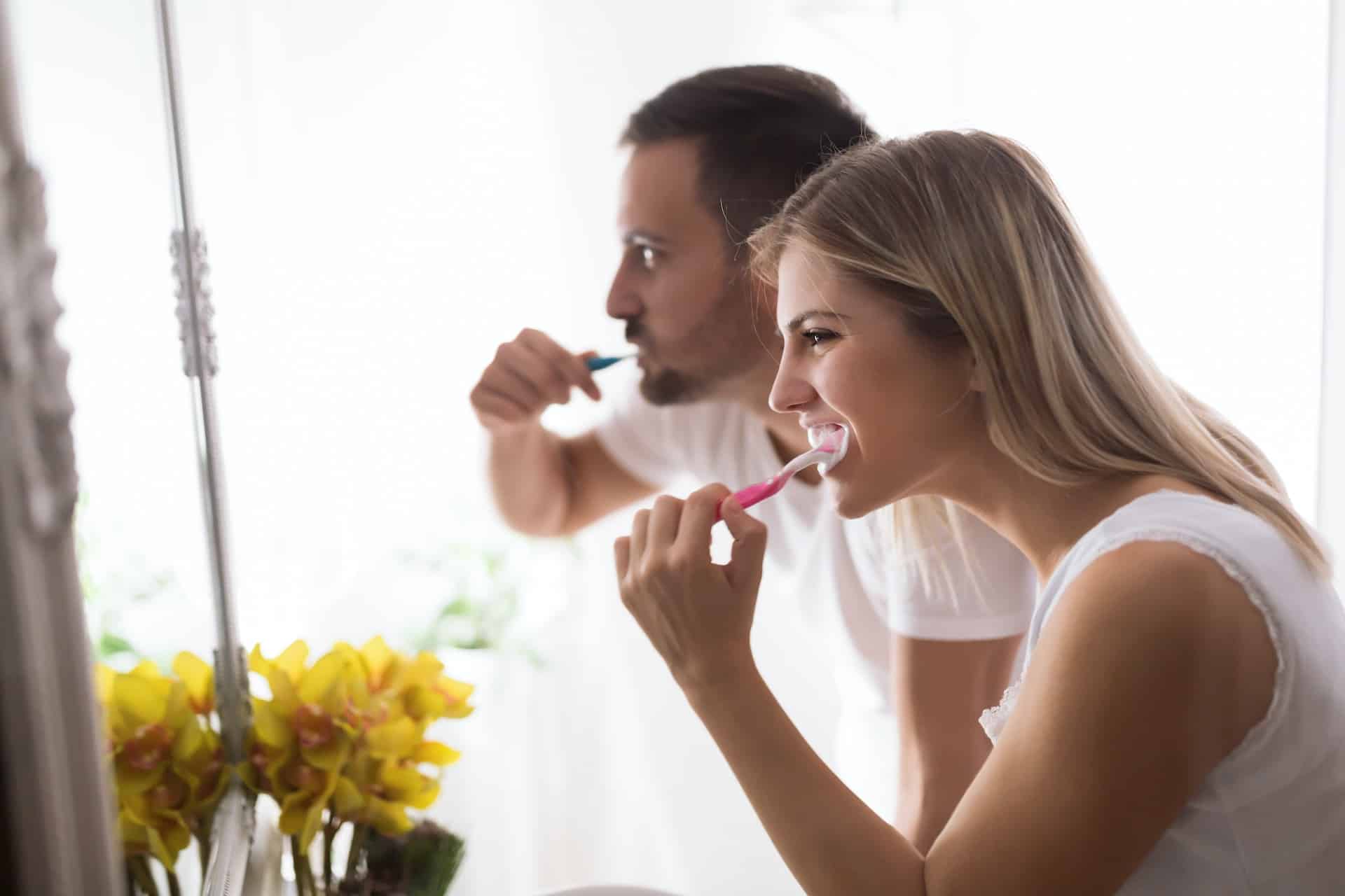 man and woman brushing teeth