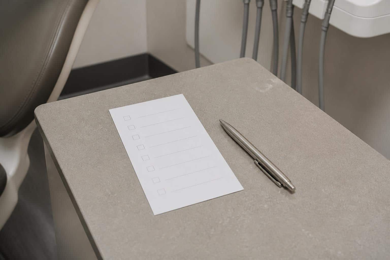 Blank appointment checklist and pen beside a dental chair