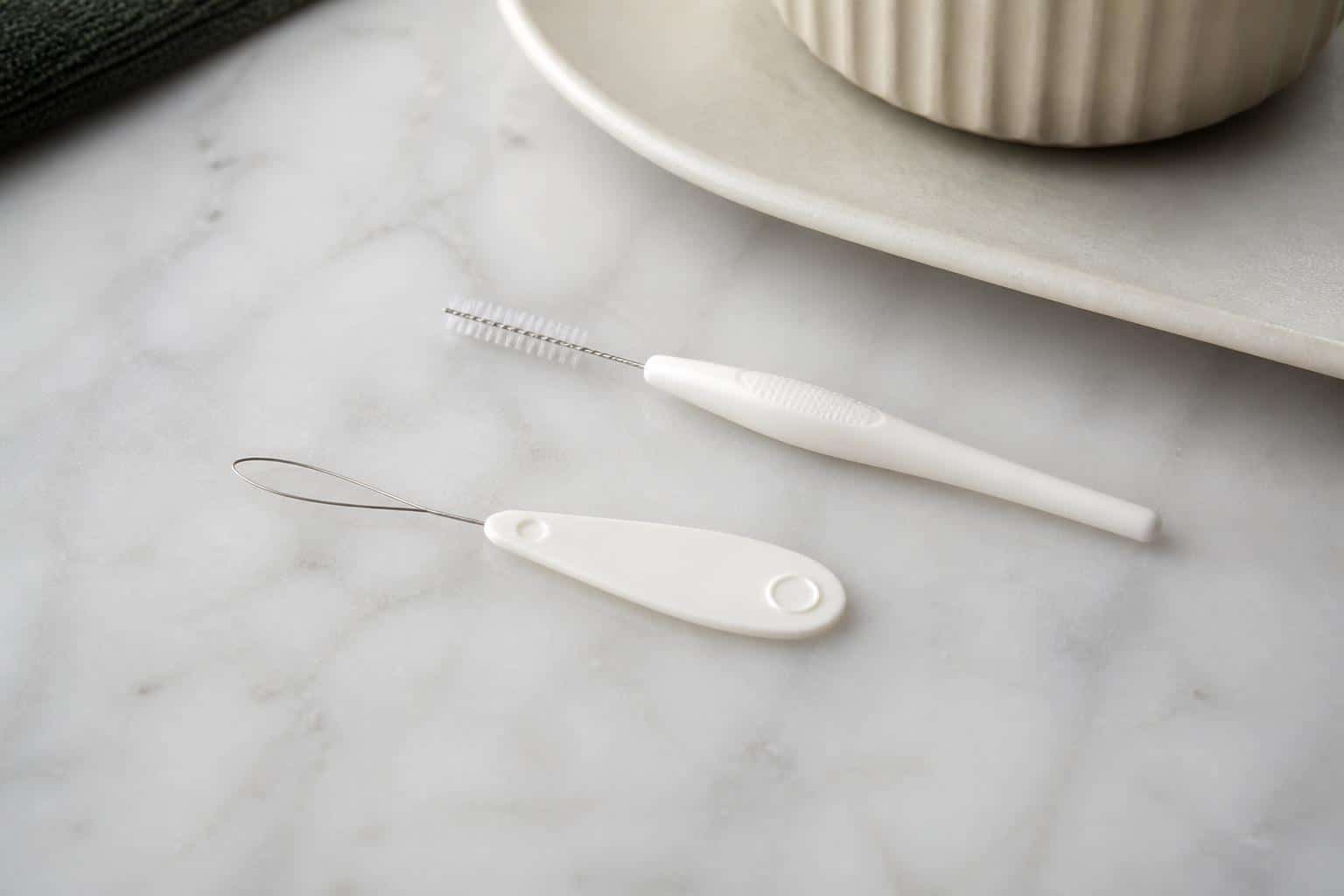 Floss threader and interdental brush on a bathroom counter