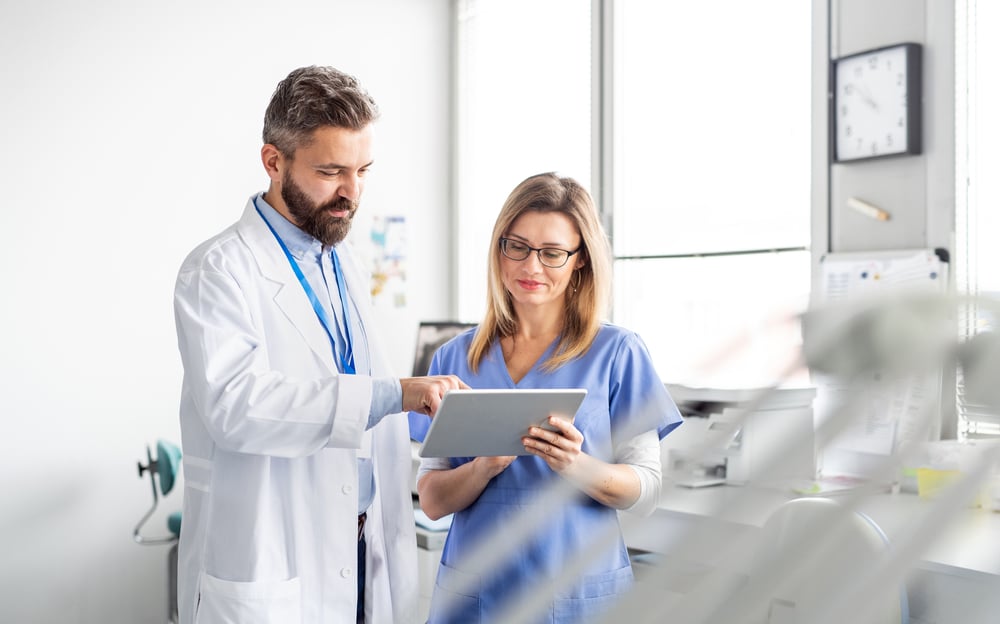 Two dental clinicians reviewing an appointment plan on a tablet