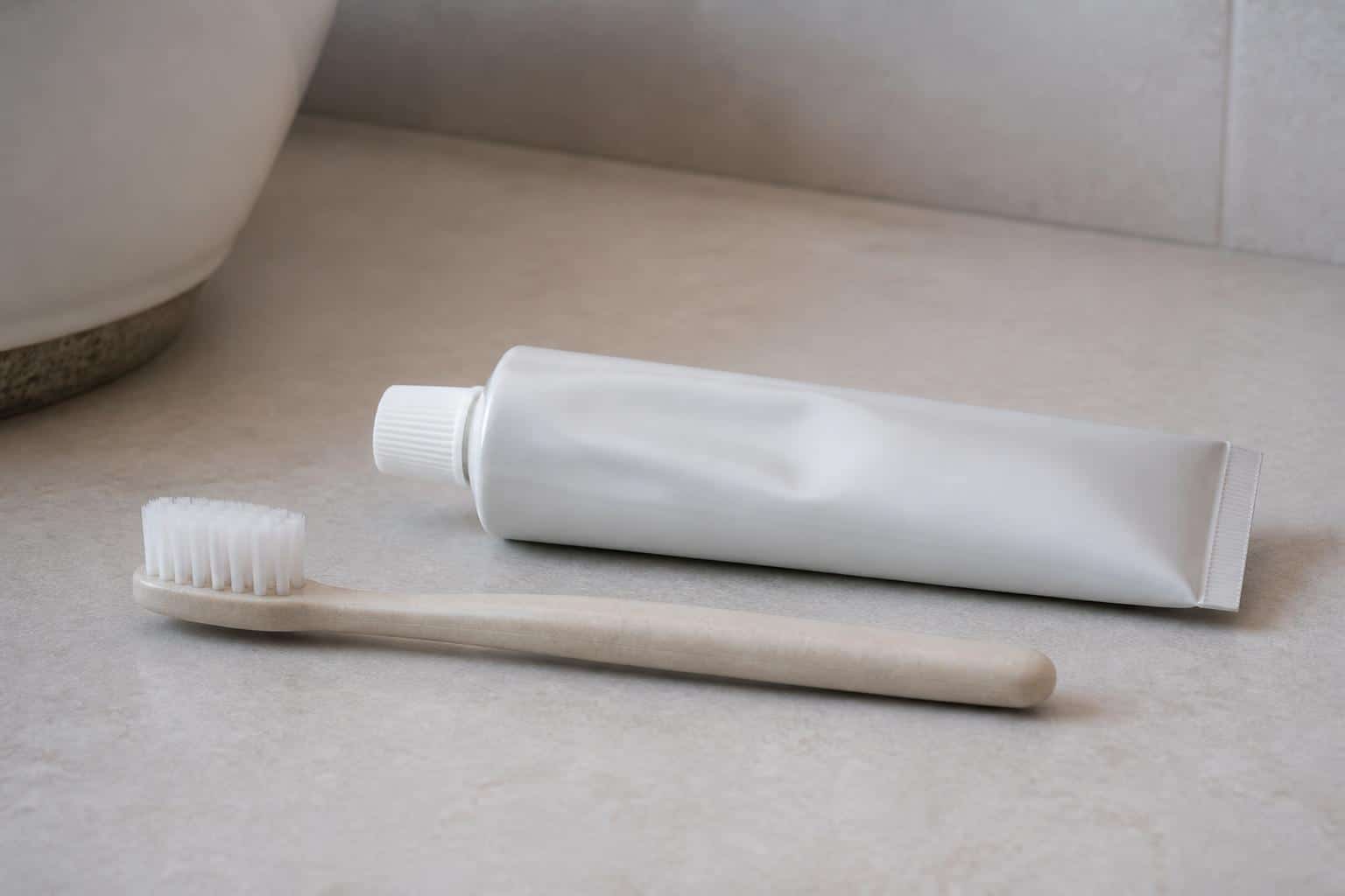 Soft toothbrush and plain toothpaste tube on a bathroom counter