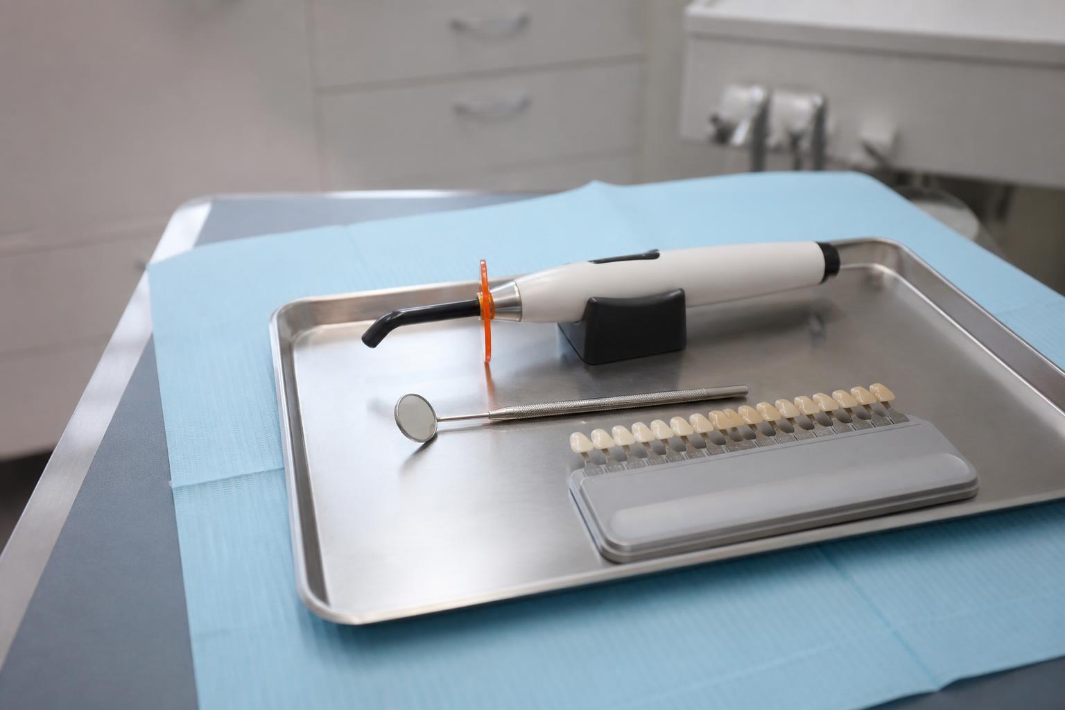 Dental tray with a mouth mirror, curing light and tooth shade guide used for bonding