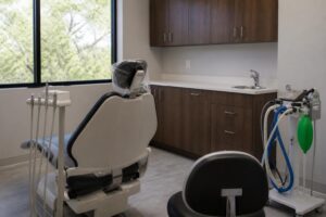 Empty dental treatment room with a dental chair and a nitrous oxide delivery unit beside it