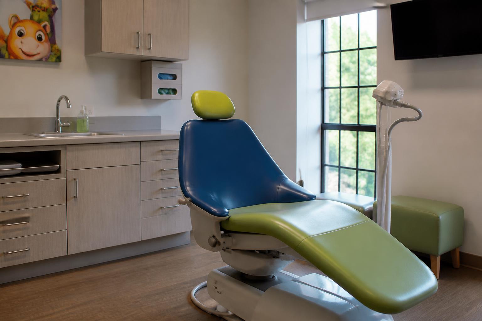Empty pediatric dental exam room with a colorful child-friendly dental chair and a curing light on its stand