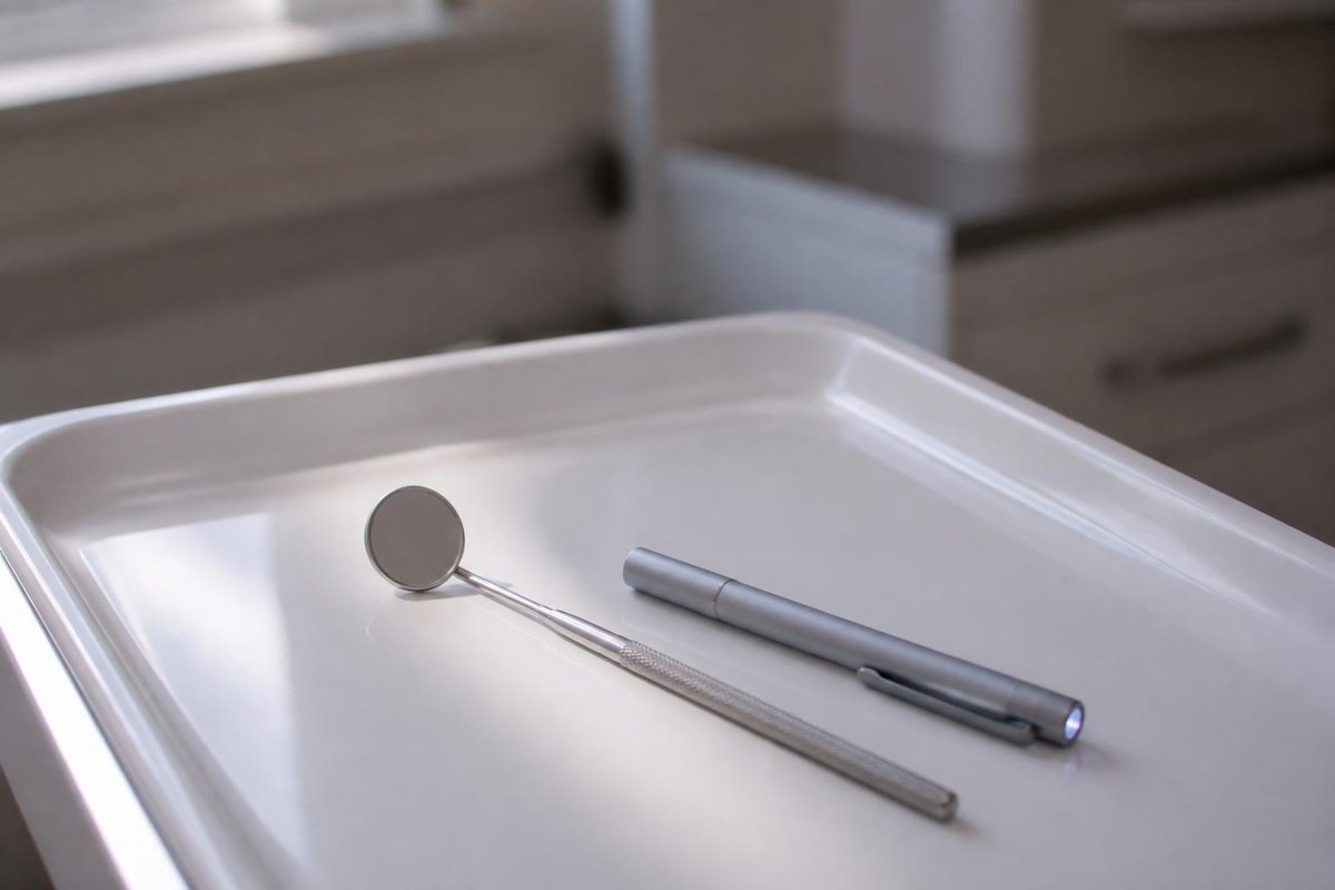 A dental mirror and penlight on a clean tray